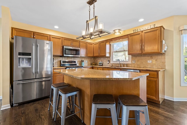 kitchen with dark hardwood / wood-style flooring, pendant lighting, a center island, and stainless steel appliances