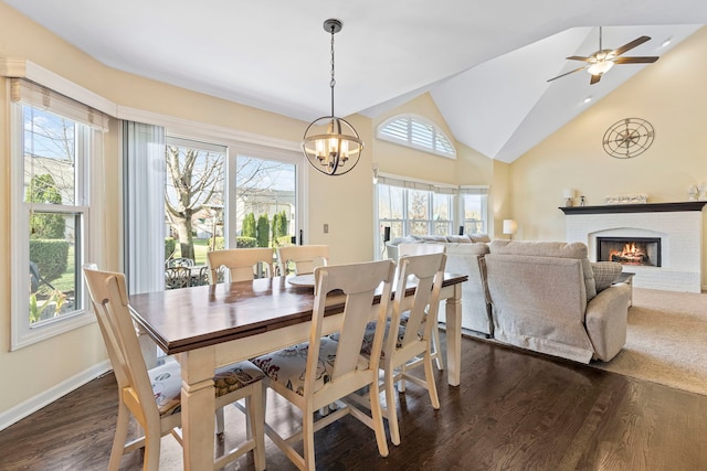 dining room with dark hardwood / wood-style flooring, a fireplace, a wealth of natural light, and vaulted ceiling