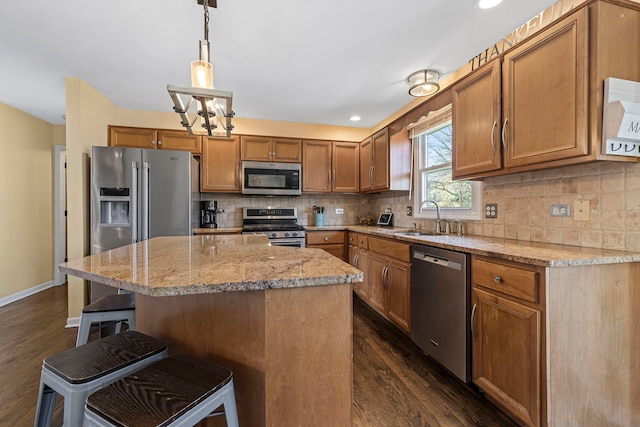 kitchen with a center island, sink, hanging light fixtures, stainless steel appliances, and dark hardwood / wood-style flooring