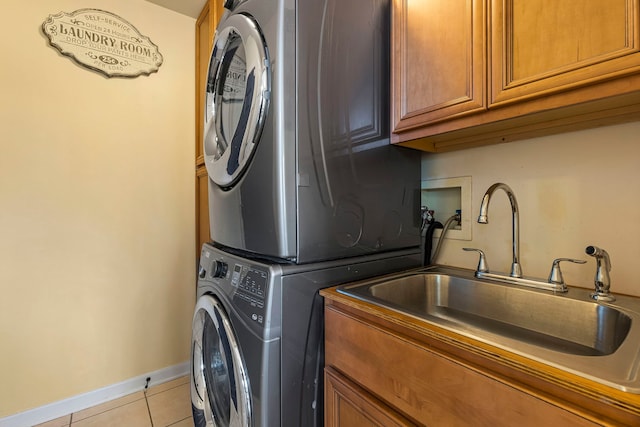 laundry area with sink, light tile patterned floors, cabinets, and stacked washer and clothes dryer