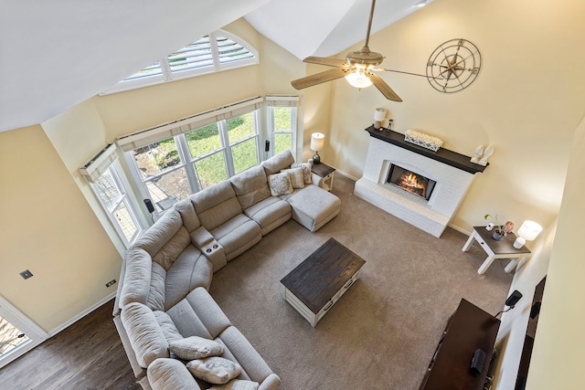 living room featuring ceiling fan, hardwood / wood-style floors, high vaulted ceiling, and a brick fireplace