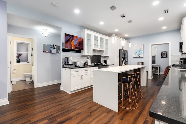 kitchen with pendant lighting, dark hardwood / wood-style flooring, black fridge, and white cabinets