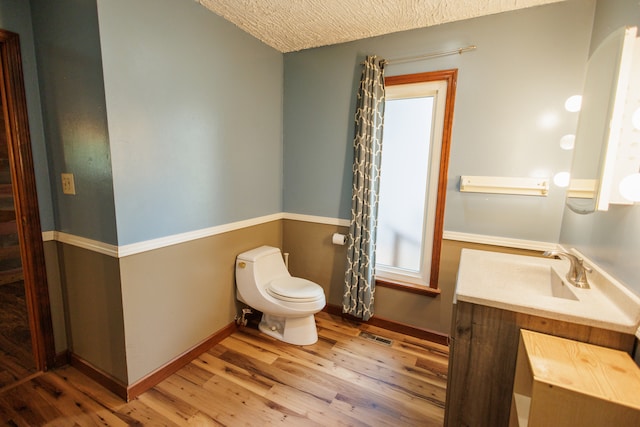 bathroom featuring vanity, toilet, wood-type flooring, and a textured ceiling