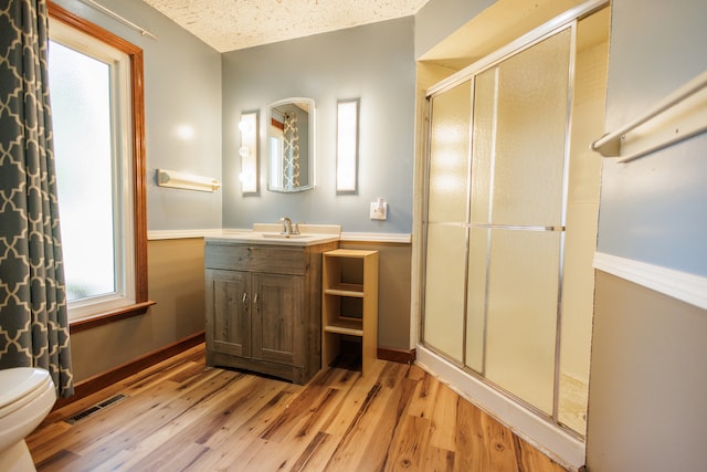 bathroom with vanity, toilet, a textured ceiling, walk in shower, and wood-type flooring