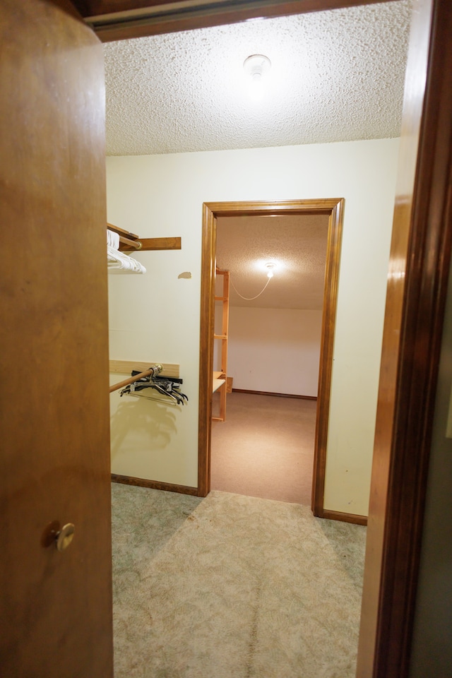 hall with light colored carpet and a textured ceiling