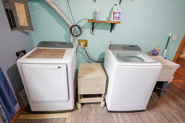 laundry room featuring washer and dryer, wood-type flooring, and electric panel