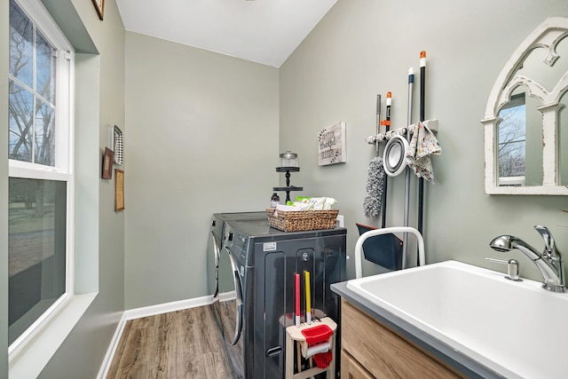 clothes washing area with laundry area, wood finished floors, a sink, baseboards, and washer and clothes dryer