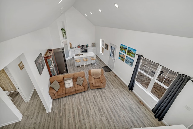 living area with baseboards, vaulted ceiling, and wood finished floors