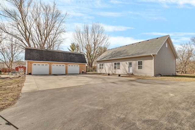 view of front of property featuring an outbuilding, a shingled roof, a garage, and entry steps