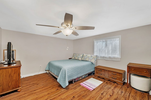 bedroom with ceiling fan, baseboards, and wood finished floors