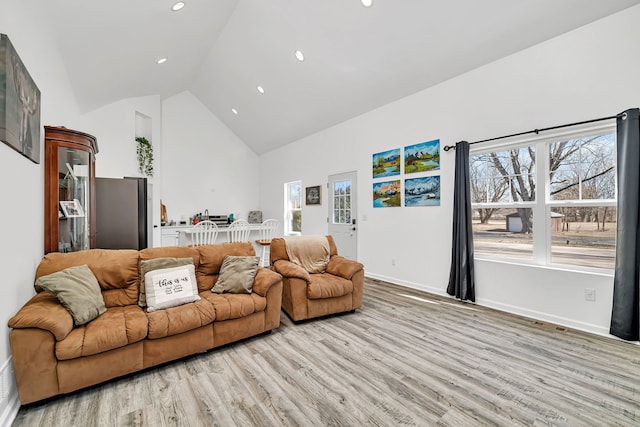 living area with recessed lighting, visible vents, light wood-style floors, high vaulted ceiling, and baseboards