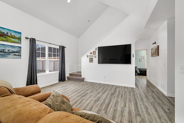 living room with lofted ceiling, wood finished floors, visible vents, baseboards, and stairway