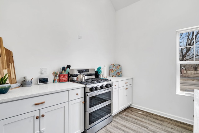 kitchen with light wood-style floors, double oven range, baseboards, and white cabinetry