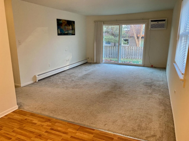 empty room with baseboard heating, a wall unit AC, and light wood-type flooring