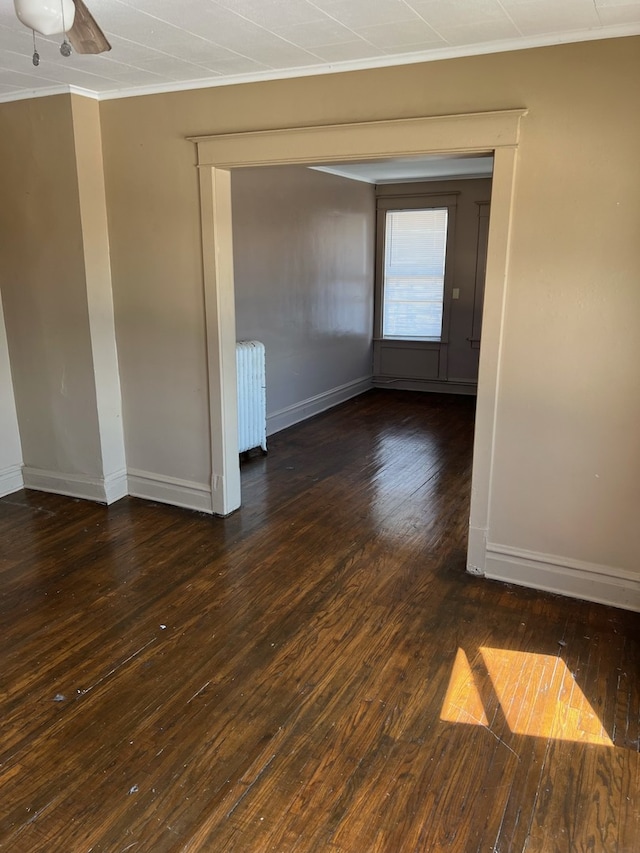 unfurnished room featuring dark hardwood / wood-style flooring, radiator, crown molding, and ceiling fan