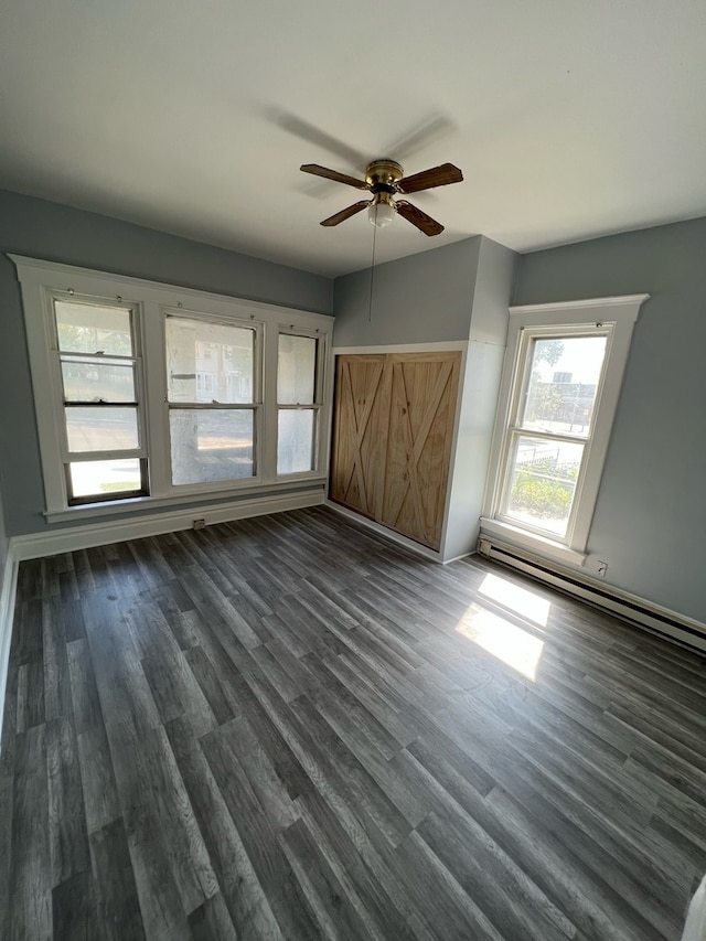 unfurnished bedroom featuring ceiling fan, dark wood-type flooring, and a baseboard heating unit