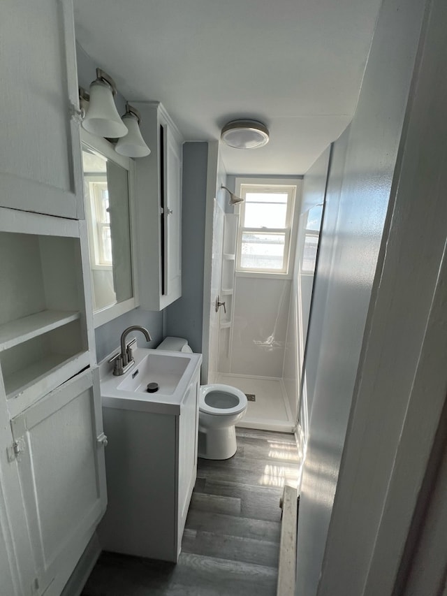 bathroom featuring hardwood / wood-style floors, vanity, toilet, and walk in shower