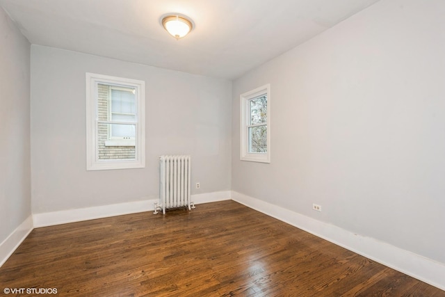 spare room with radiator heating unit and dark hardwood / wood-style floors