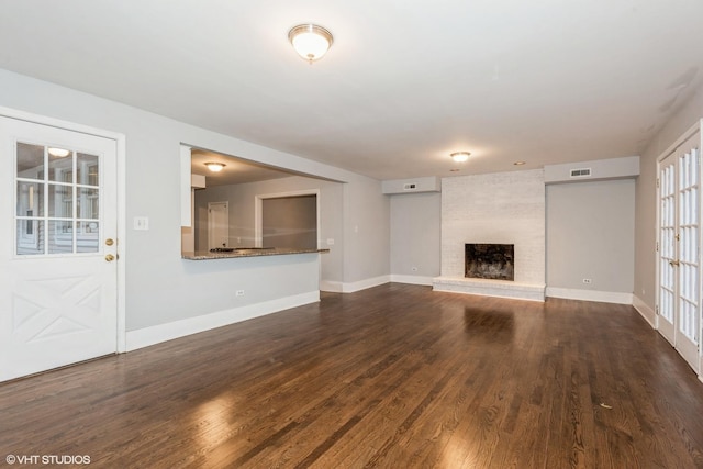 unfurnished living room with a fireplace and dark wood-type flooring