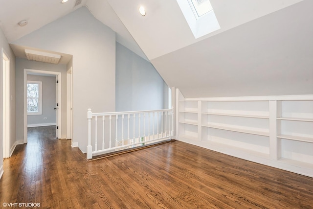 additional living space with built in shelves, vaulted ceiling with skylight, and dark hardwood / wood-style floors