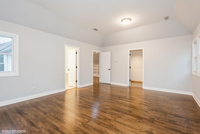 unfurnished bedroom featuring ensuite bathroom, dark hardwood / wood-style flooring, a spacious closet, and vaulted ceiling