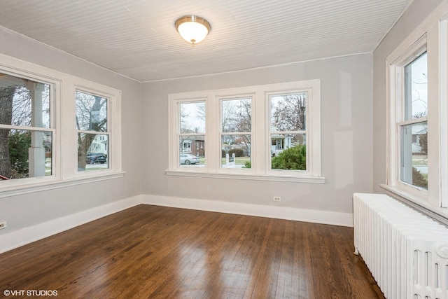 unfurnished room with dark hardwood / wood-style floors and radiator