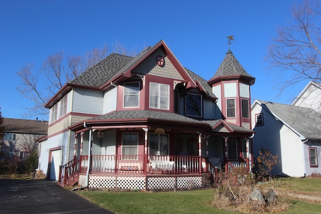 victorian house with a garage, a front yard, and covered porch