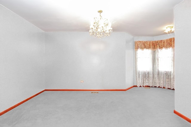 carpeted empty room with an inviting chandelier