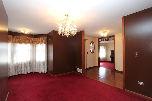 carpeted spare room with an inviting chandelier