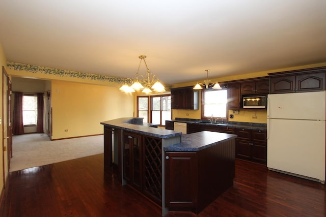 kitchen with an inviting chandelier, dark brown cabinets, hanging light fixtures, a kitchen island, and white fridge