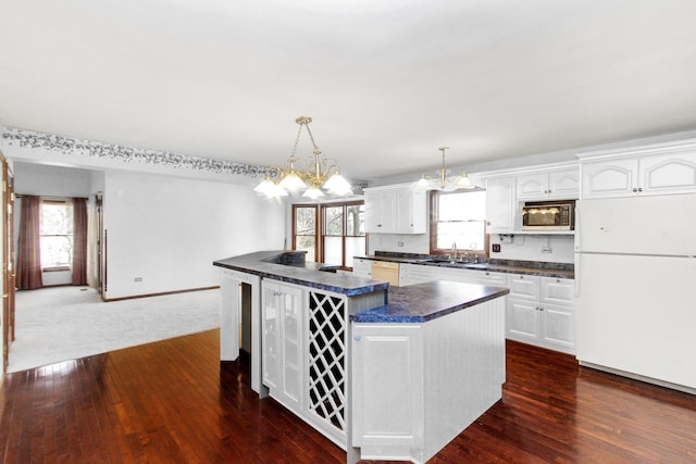 kitchen featuring white refrigerator, white cabinetry, hanging light fixtures, and sink