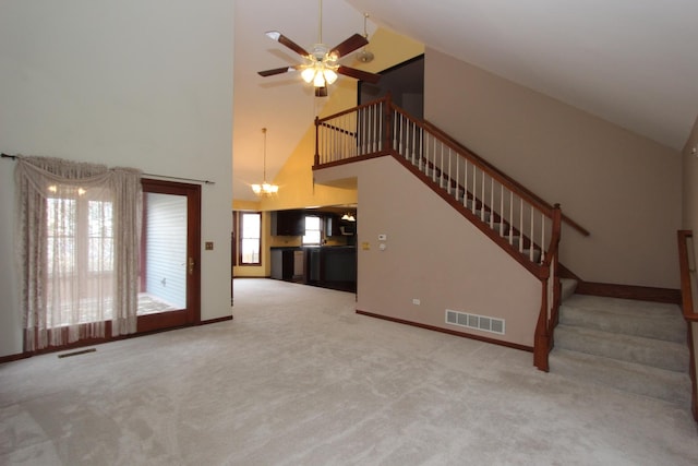 unfurnished living room with ceiling fan with notable chandelier, carpet, and a high ceiling