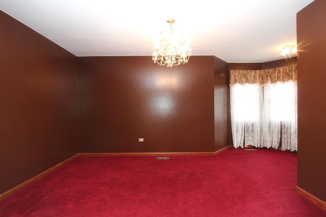 carpeted spare room with a chandelier