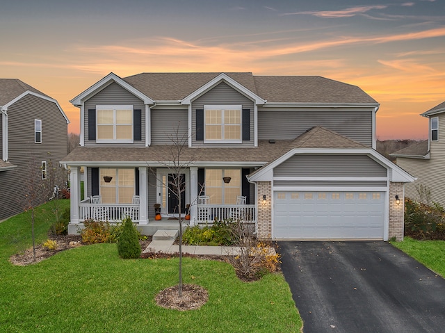 view of front of house featuring covered porch, a yard, and a garage