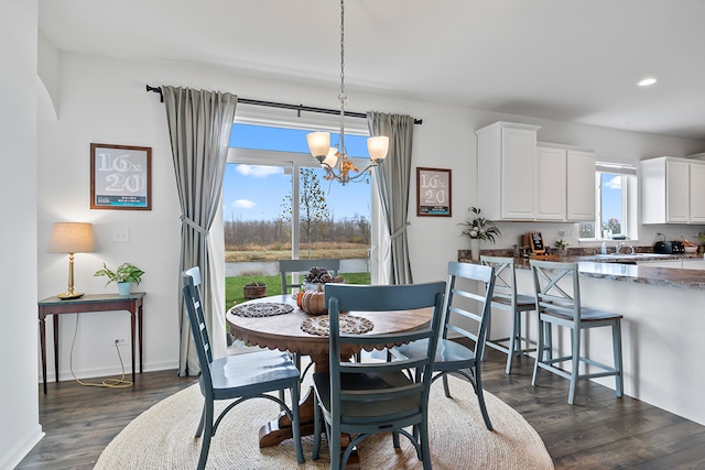 dining room with a wealth of natural light, dark wood-type flooring, and an inviting chandelier