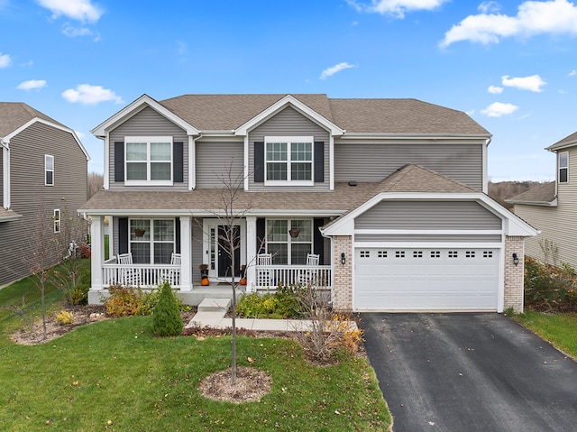 view of property featuring a porch, a garage, and a front lawn