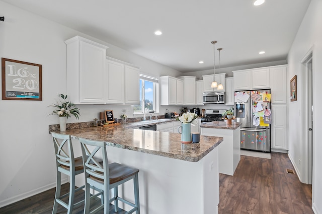 kitchen featuring pendant lighting, dark hardwood / wood-style floors, white cabinetry, and appliances with stainless steel finishes