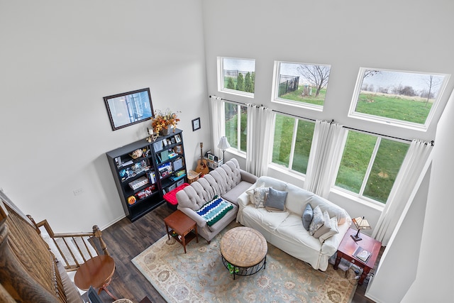 living room with plenty of natural light, dark wood-type flooring, and a high ceiling