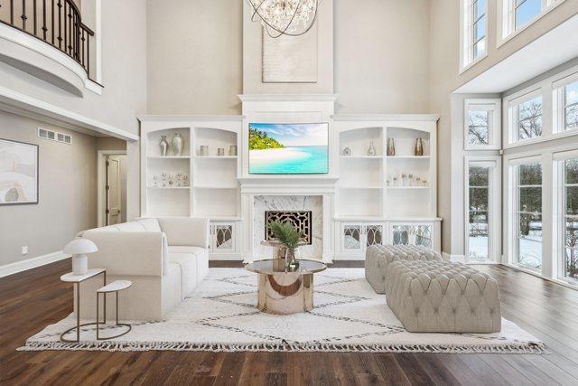 living room with a premium fireplace, a towering ceiling, wood-type flooring, and an inviting chandelier