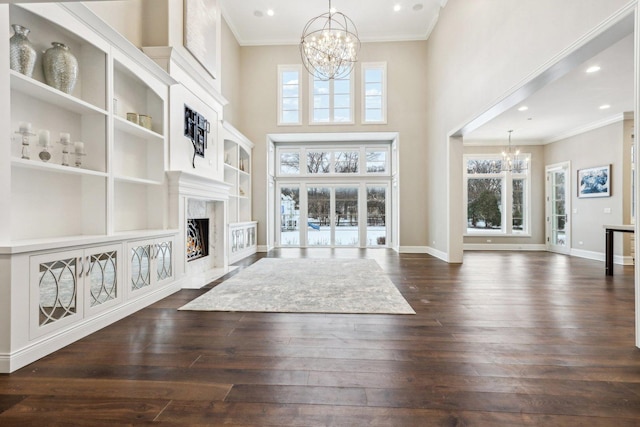 unfurnished living room with dark wood-type flooring, a high end fireplace, and an inviting chandelier