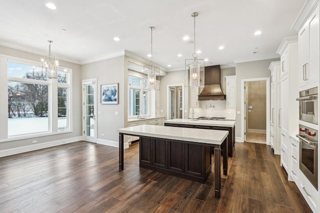 kitchen with a large island with sink, pendant lighting, a kitchen breakfast bar, custom range hood, and white cabinets