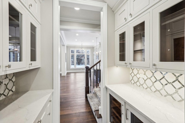 interior space with wine cooler, dark wood-type flooring, a chandelier, and ornamental molding