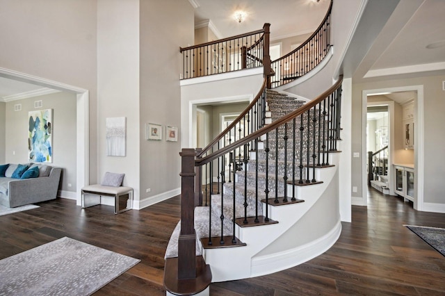 stairway with a high ceiling, crown molding, and hardwood / wood-style flooring