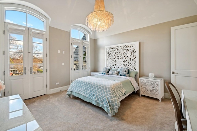 carpeted bedroom with an inviting chandelier and french doors