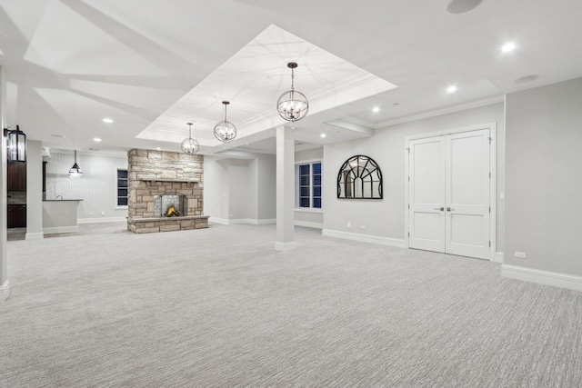 unfurnished living room featuring crown molding, light colored carpet, a fireplace, and a tray ceiling