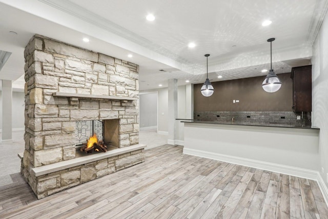 unfurnished living room with light hardwood / wood-style flooring, crown molding, and a stone fireplace