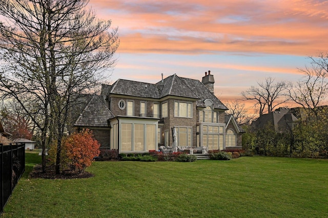 back house at dusk with a lawn