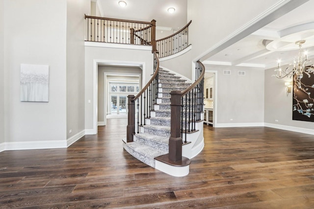 entrance foyer featuring dark wood-type flooring, coffered ceiling, an inviting chandelier, and beamed ceiling