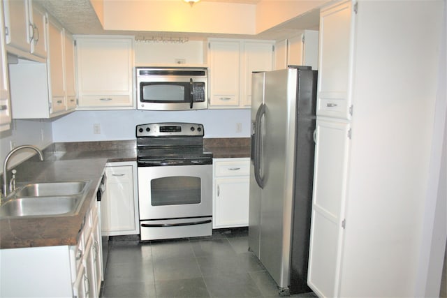 kitchen featuring white cabinets, sink, stainless steel appliances, and dark tile patterned flooring