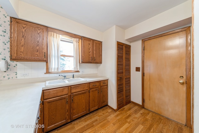 kitchen with decorative backsplash, light hardwood / wood-style floors, and sink